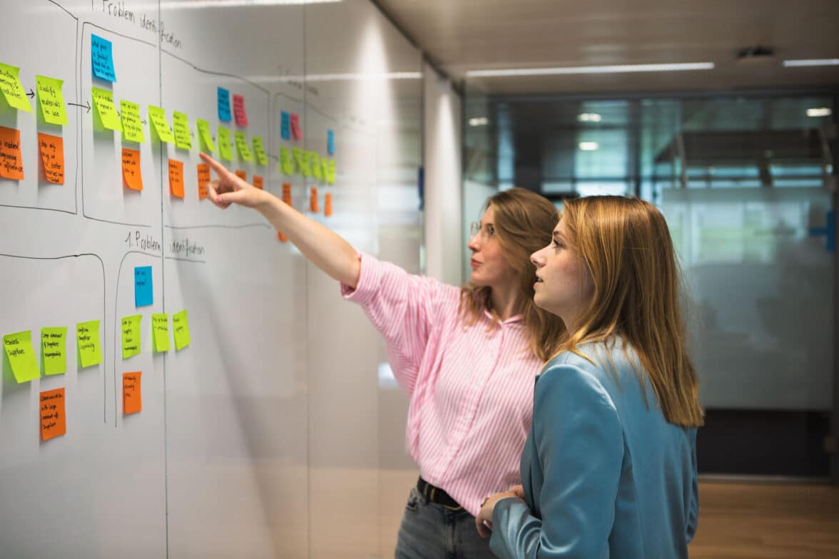 Twee consultants wijzen naar een whiteboard