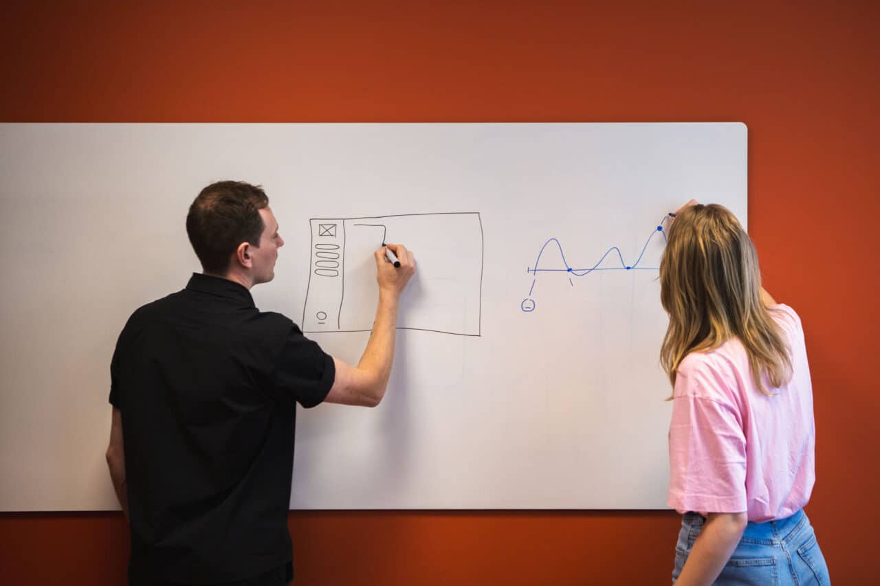 Twee GriDD consultants schrijven op een whiteboard